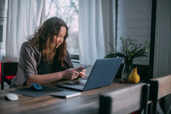 에서의 여성은 집에서 노트북으로 일하고 거실의 소파에 앉아서 전화로 이야기를 — 스톡 사진