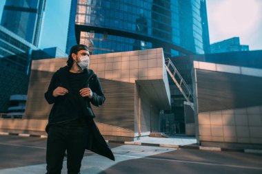 Gökdelenlerin endüstriyel arka planında tıbbi maskeli bir adam. Boş bir metropolde maskeli yalnız bir genç adam. İnsan ve dev şehir karantinada.