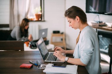 Kadınlar oturma odasında dizüstü bilgisayarlarla oturur, ekrana bakar, notlar alır, yabancı bir dil öğrenir, online bir eğitim kursu okur, internetten öğrenir, müşteriye video yoluyla danışır.
