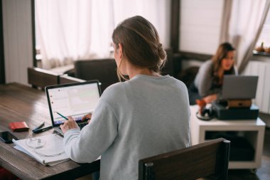 Kadınlar oturma odasında dizüstü bilgisayarlarla oturur, ekrana bakar, notlar alır, yabancı bir dil öğrenir, online bir eğitim kursu okur, internetten öğrenir, müşteriye video yoluyla danışır.