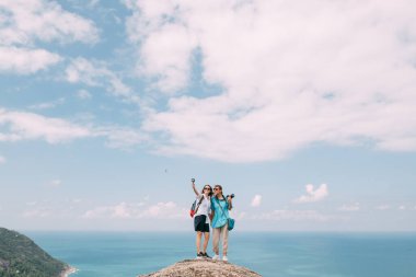 Uçurumun kenarındaki kadın fotoğrafçılar okyanusun destansı manzarasına sahipler. Popüler bir turizm merkezi. Tropik bölgelerde tatilde olan bir adam. Asya Maceraları.