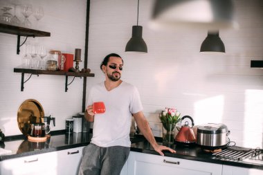 Yüzünde yamalar olan bir adam dinleniyor. Erkeklerin kişisel bakımı. Genç yakışıklı adam yüzüne bakar, mutfakta çay içer..