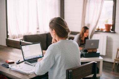 Kadınlar oturma odasında dizüstü bilgisayarlarla oturur, ekrana bakar, notlar alır, yabancı bir dil öğrenir, online bir eğitim kursu okur, internetten öğrenir, müşteriye video yoluyla danışır.