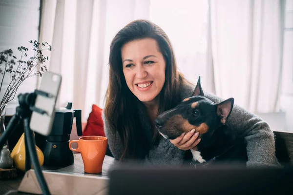 Woman talking online, taking selfie with dog at home. A young girl is photographed with a rottweiler. Girl talking on video calling and hugs a dog