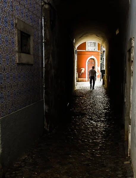 A person in a dark corridor with a red building in the bottom