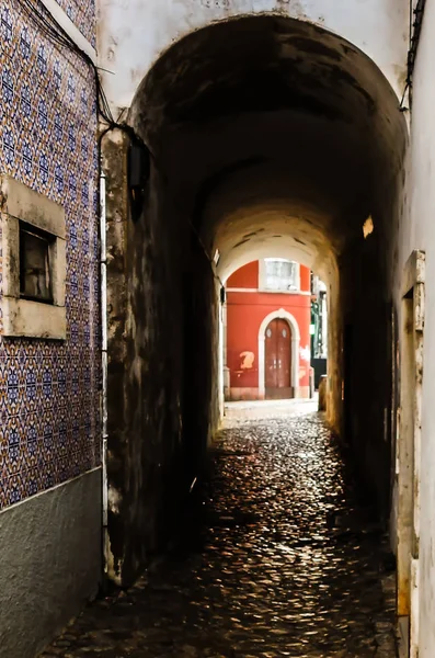 A dark corridor with a red building in the bottom