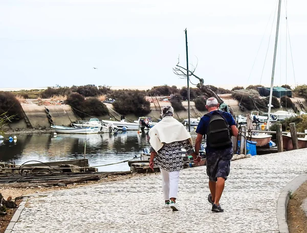 A man and a woman walking by the hand beside the boats