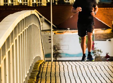 Siyah kıyafetli koşucu sabahları köprüye tırmanıyor.