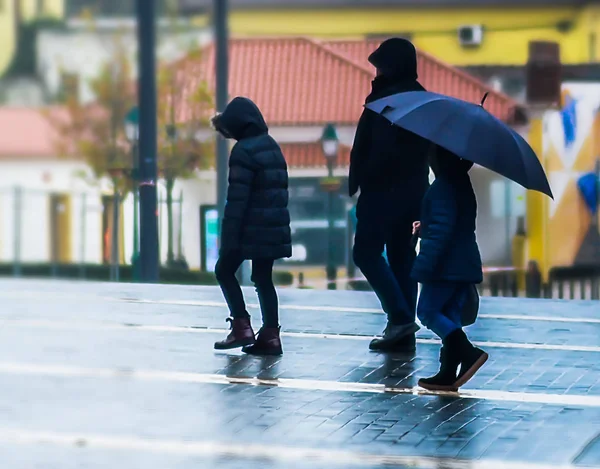 一个带着两个孩子在雨中散步的男人 — 图库照片