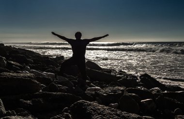 Gün batımında ellerini kaldırmış bir adamın görüntüsü