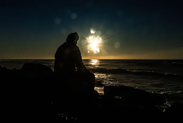 Άνθρωπος Κάθεται Μια Πέτρα Στο Φως Του Ηλιοβασιλέματος — Φωτογραφία Αρχείου