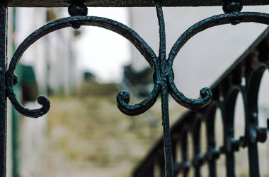 Ön planda işlenmiş demir bir çit parçası.