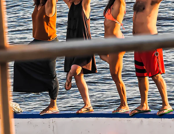 Group of people doing gymnastics on the ocean shore