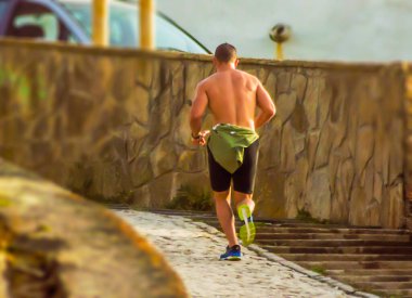 Adam duvarın ve merdivenlerin yanında koşuyor.