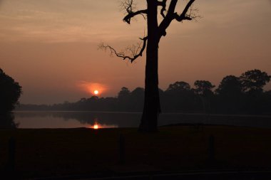 sunrise over beautiful lake in angkor wat with sun reflecting in the water