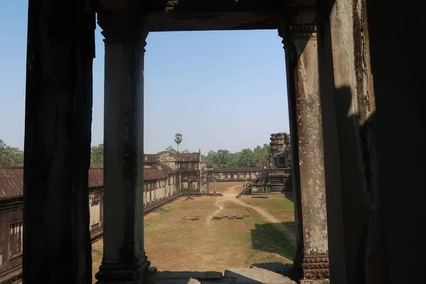 Starověký chrám s hnědou zelenou gras v angkor wat vidět skrz kamenné pilíře, trosky khmer civilizace — Stock fotografie