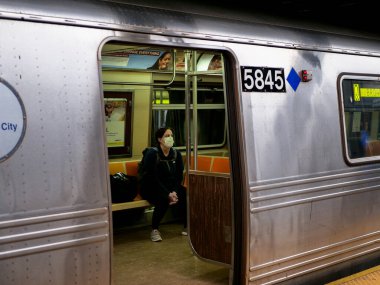 New York, ABD, 24 Mart 2020: Coronavirus salgını sırasında metro istasyonunda maske takan üzgün ve yorgun görünen bir kadın bekliyor.