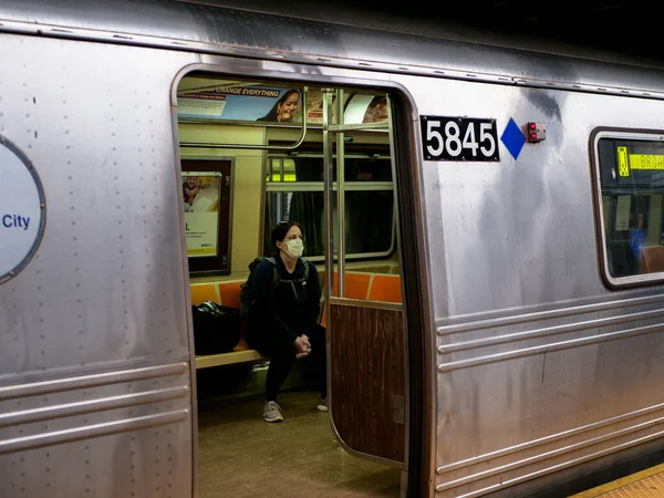 New York, United States, USA March 24, 2020: sad and tired looking woman wearing mask waiting in empty subway station during coronavirus pandemic — Stock Photo, Image