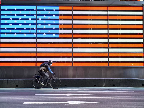 Nova York, Estados Unidos, EUA 24 de março de 2020: homem com máscara andando de bicicleta para trabalhar na praça dos tempos vazios em frente aos estados unidos da América durante a pandemia de coronavírus, surto de vírus — Fotografia de Stock