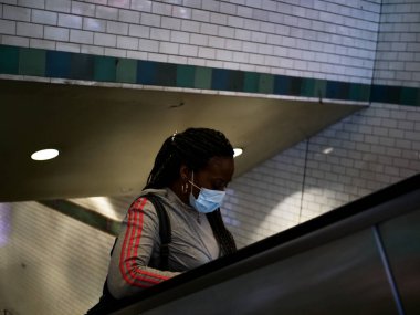New York, Amerika Birleşik Devletleri, 24 Mart 2020: Afro-Amerikan kadın metroda maske takarak salgın sırasında yalnızdı.