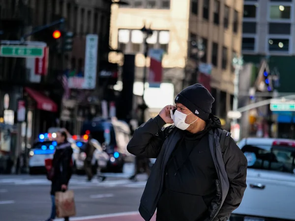 New York, Stati Uniti, Stati Uniti 26 marzo 2020: uomo preoccupato con maschera al telefono con la polizia in background durante la pandemia covid19 — Foto Stock