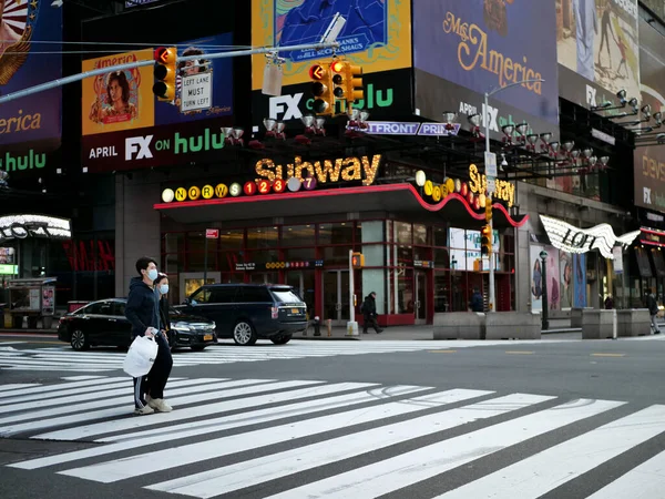 Nova York, Estados Unidos, EUA 24 de março de 2020: casal asiático com máscara na frente da estação de metrô quadrada de tempos vazios durante o surto de coronavírus, pandemia Imagens De Bancos De Imagens