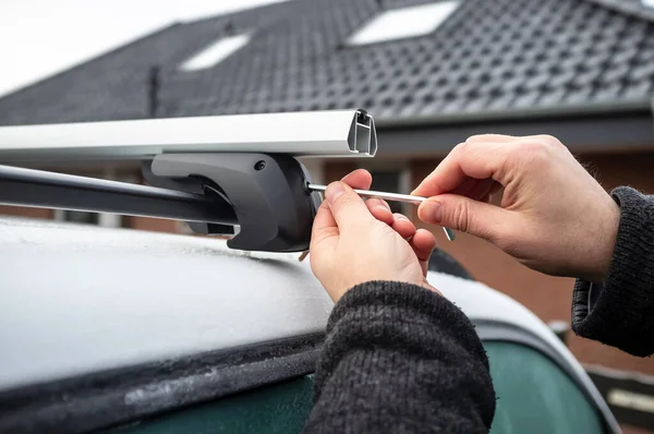 Mann mit Schraubenzieher montiert Aufsätze für Kofferraum oder Ladebox auf Autodach. — Stockfoto