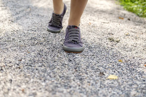 Жіночі ноги в кросівках піднімаються по сліду гравію в сонячний літній день, на розмитому тлі. Концепція активного способу життя . — стокове фото