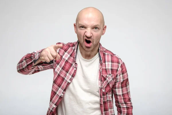 Boos, een agressieve kale man met stoppelpunten wijsvinger naar iemand en beschuldigend, kijkend naar de camera. — Stockfoto