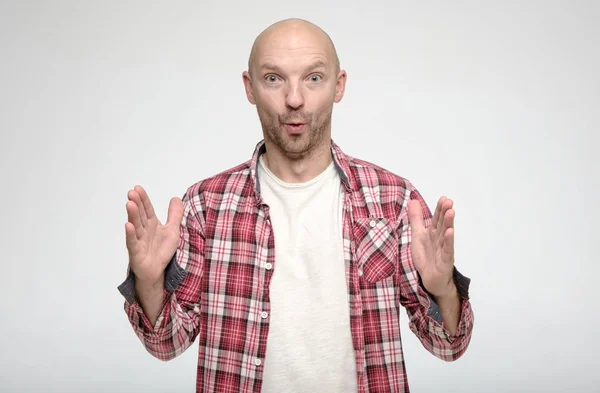 Shocked bald man showing huge size gesture with hands and looks in surprise with big eyes at the camera. — Stock Photo, Image