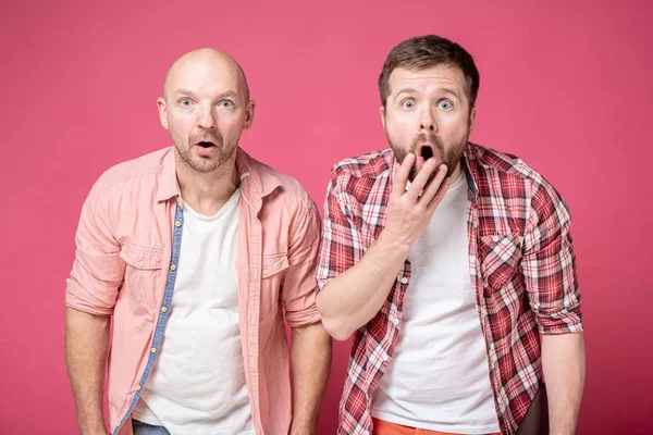 Portret van twee geschokte jongeren die uit een onverwachte verrassing hun mond opendeden en verbaasd naar de camera keken. — Stockfoto