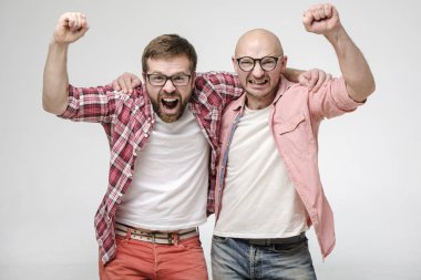 Neşeli adamlar ellerini kaldırır, zaferi hissederler, gülümser ve yüzlerinde mutlu bir ifadeyle kameraya bakarlar..