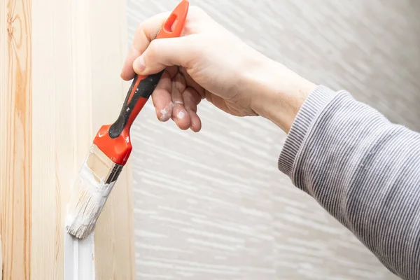 Reparación. La mano con un pincel pinta una puerta de madera en color blanco . —  Fotos de Stock