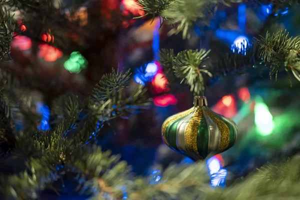 Beau jouet en verre multicolore sur un arbre de Noël, sur un fond flou de guirlande . — Photo
