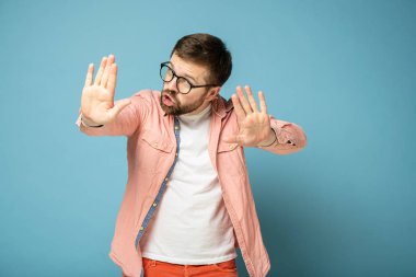 Adam, avuç içlerini ileri doğru tutarak ve kameraya ciddi ciddi bakarak birine dur işareti yaparak güvence verir..
