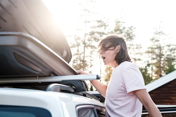 Mujer mira en el maletero abierto o caja de carga, que se encuentra en el techo del coche y se da cuenta de que se olvidó de algo importante . — Foto de Stock