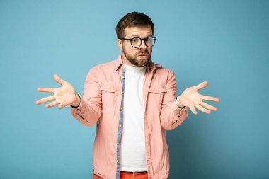 Man is excited and bewildered, he is amazed at what is happening, looks inquiringly at the camera and makes a gesture with hands.