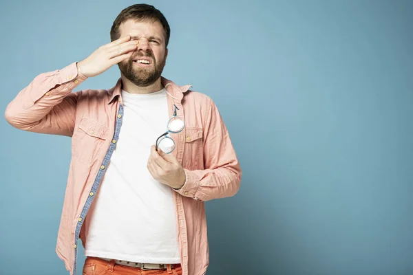 De man voelt zich ongemakkelijk, doet zijn bril af en wrijft over zijn ogen. Kopieerruimte. — Stockfoto