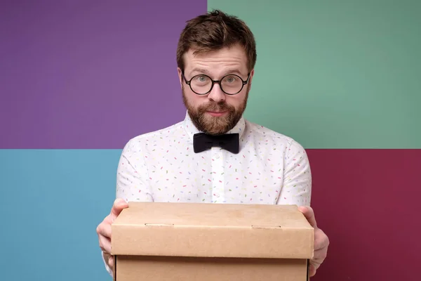 Hombre satisfecho con gafas redondas sosteniendo una caja y está a la espera de una agradable sorpresa . — Foto de Stock