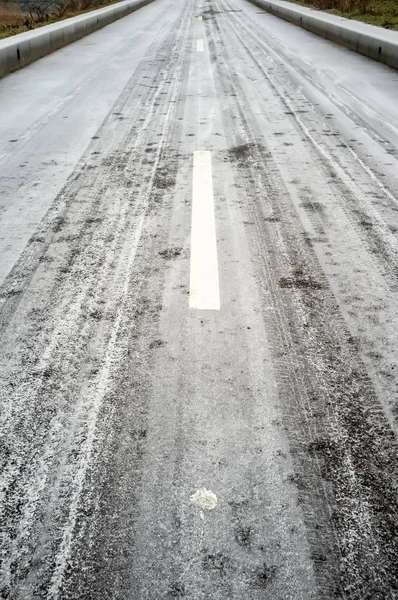 Estrada de asfalto congelada com marcações, freios e calçadas, em nevoeiro, num dia frio de inverno . — Fotografia de Stock
