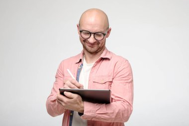 Gözlüklü neşeli, sevimli, gülümseyen adam, tablet ve stil kalemle çalışıyor..