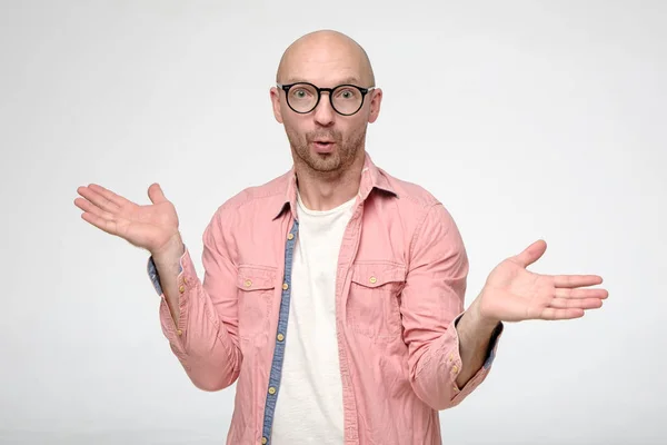 Can not be. Surprised bald man with glasses, spreads hand to the sides and looks into the camera with big eyes. — Stock Photo, Image