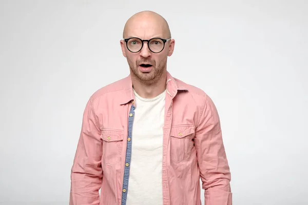 Impresionado, hombre calvo molesto con gafas en un estupor, la boca emocionalmente abierta y mira a la cámara en incredulidad . — Foto de Stock