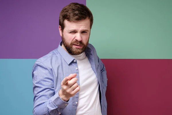 Cute Caucasian bearded man accuses someone, points with index finger and looks confidently with squinted eyes. — 스톡 사진