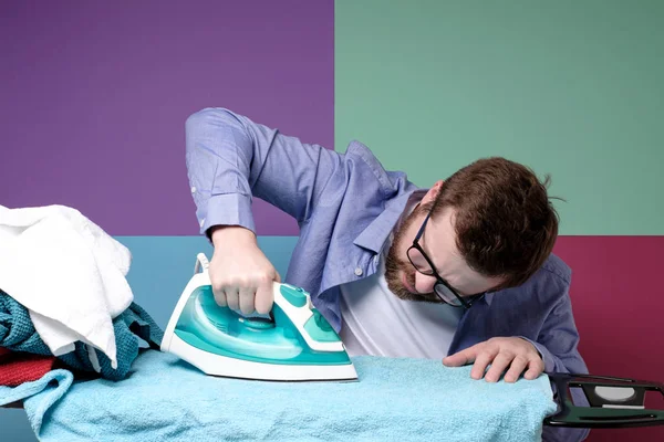Бородатий чоловік в окулярах старанно випрасував чисту білизну на дошці. Домашнє завдання . — стокове фото