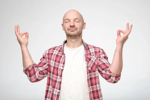 Hombre tranquilo y relajado con los ojos cerrados, que está meditando y tratando de encontrar armonía y equilibrio . — Foto de Stock