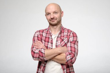 Sakin adam kollarını kavuşturmuş, yorgun gözlerle kameraya bakıyor..