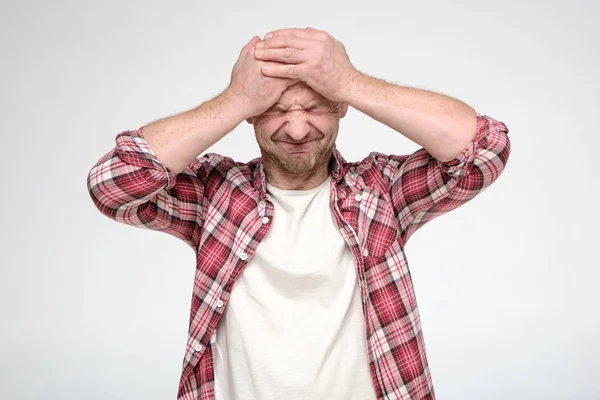 Mann leidet unter starken Kopfschmerzen oder erlebt Stress, er quetscht Kopf mit Händen und geschlossenen Augen. — Stockfoto