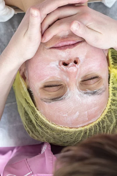 Esteticista profissional massageando com as mãos aplica uma máscara cosmética e relaxante ao rosto após o descascamento químico . — Fotografia de Stock
