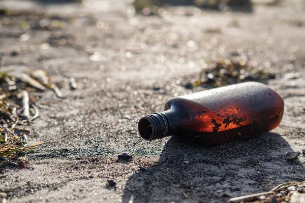 Garbage on the beach. Bottle in the sand on a sunny day. Environmental pollution. Human trash. — Stock Photo, Image